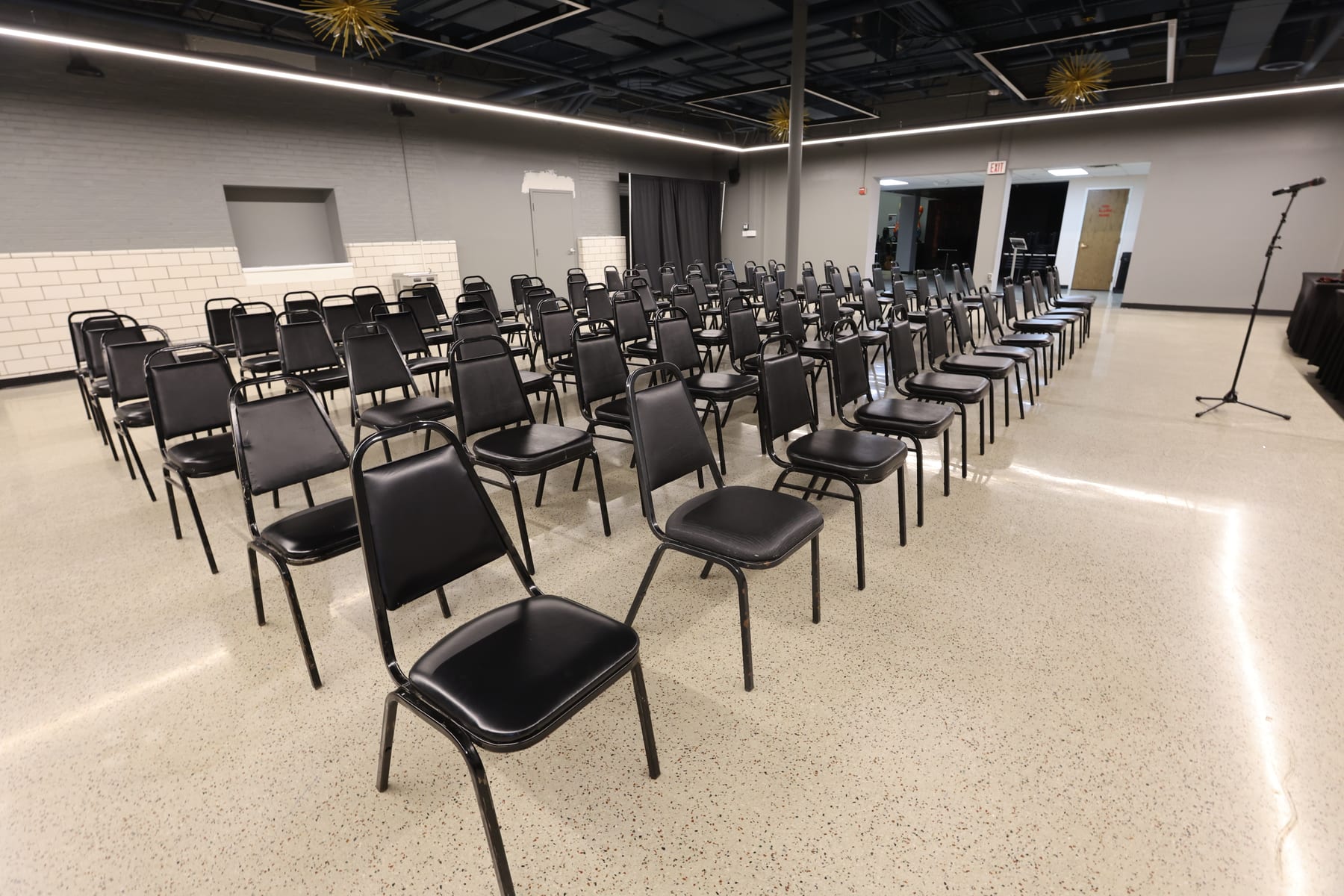 Rows of chairs seen from the last row, a microphone stand at the front