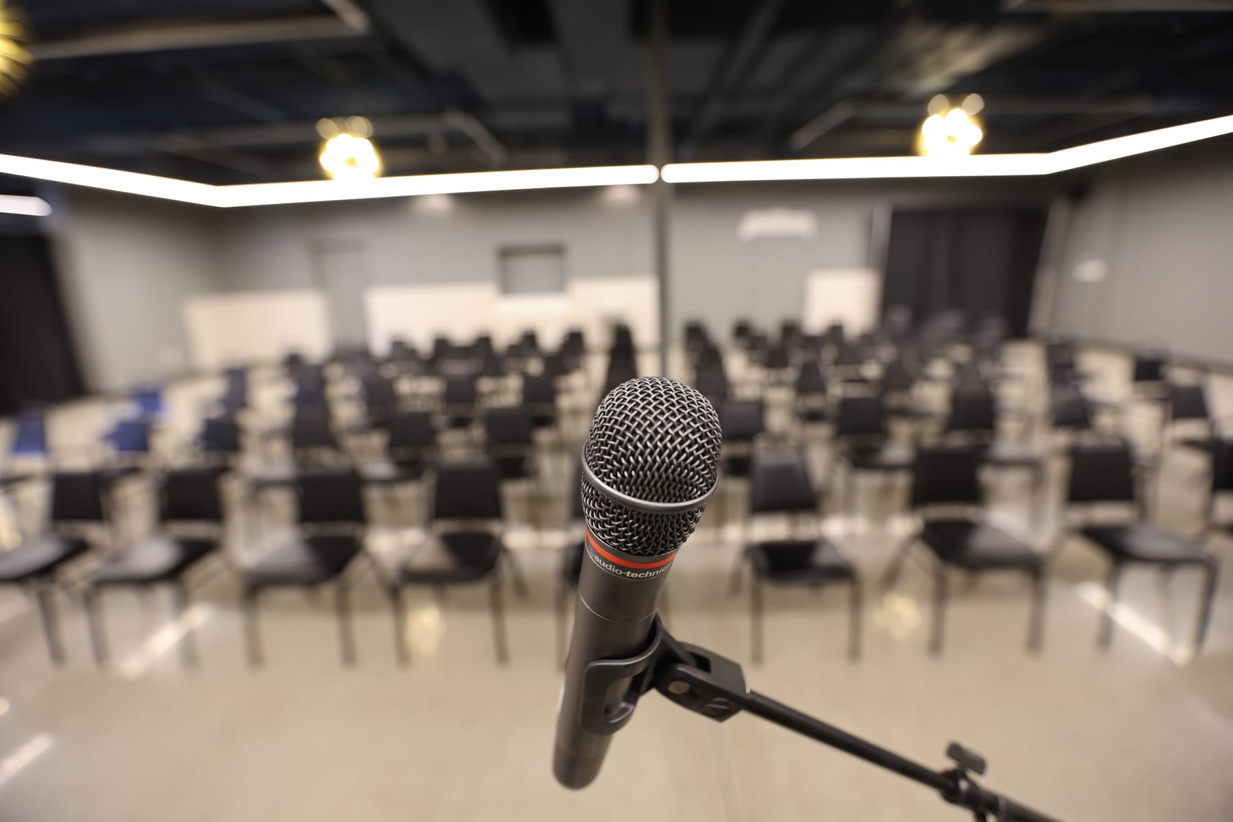 A wireless microphone on its stand, the rows soft behind it